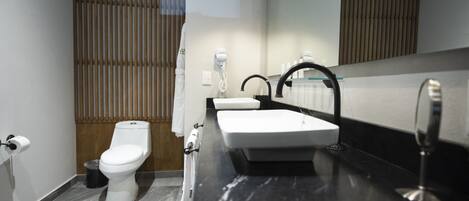 Un baño moderno con inodoro, lavamanos y espejo.