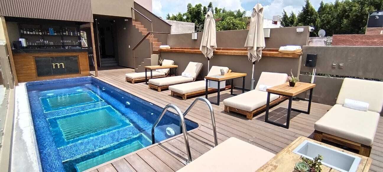 A rooftop pool area with lounge chairs, a bar, and a hot tub.