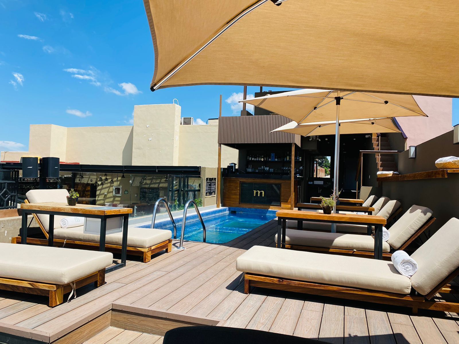 A rooftop pool area with lounge chairs, a bar, and a pool.