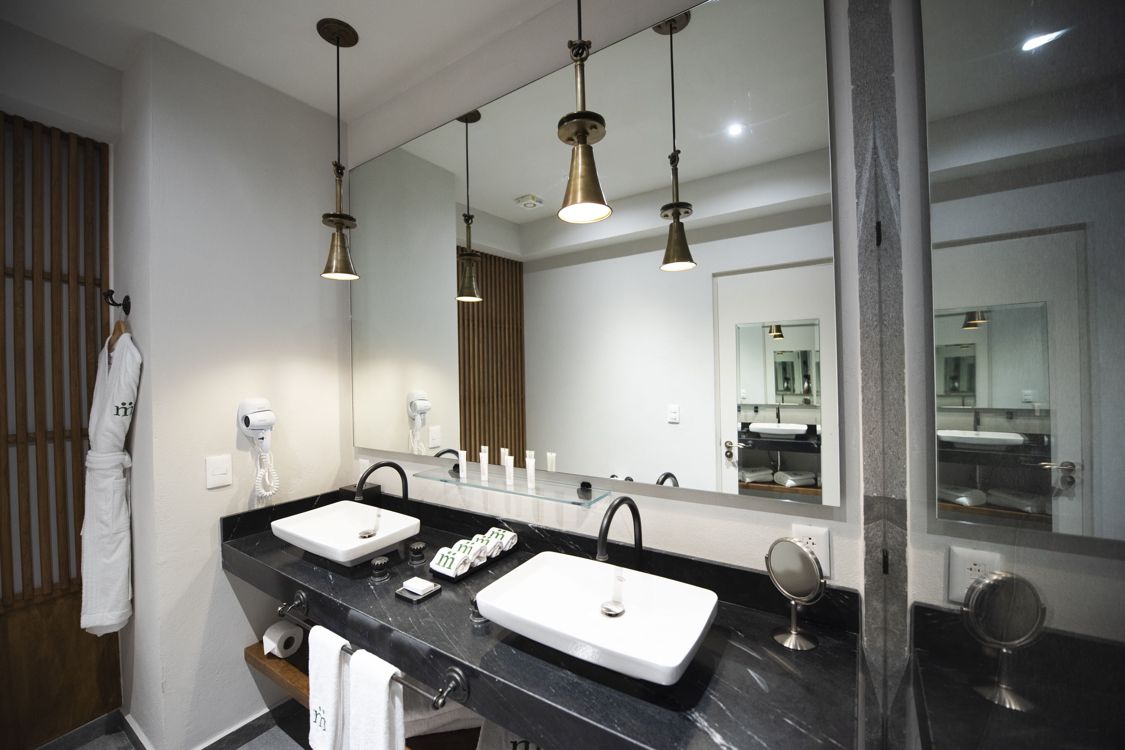 Une salle de bain moderne avec deux vasques, un grand miroir et des luminaires suspendus.