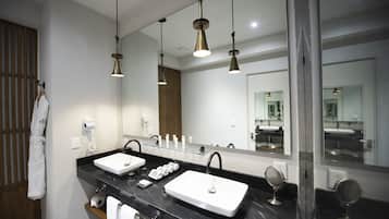 A modern bathroom with two sinks, a large mirror, and pendant lighting.
