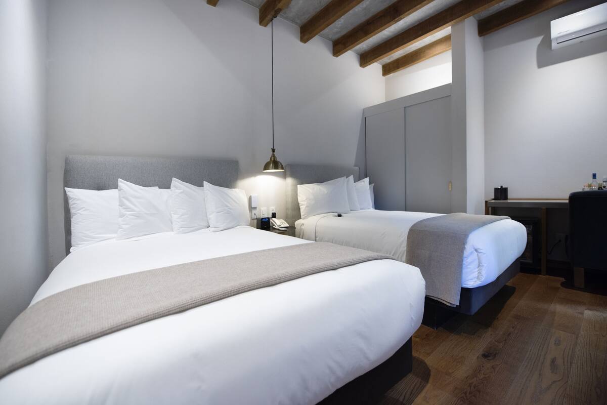 Habitació d'hotel amb dos llits, un escriptori i un armari.