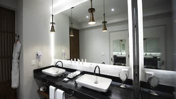 A modern bathroom with two sinks, a large mirror, and hanging pendant lights.
