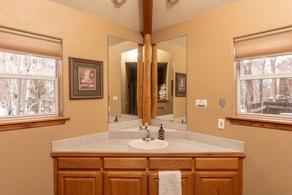 A bathroom with a wooden vanity, a large mirror, and framed artwork on the walls.