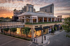 A hotel with a modern architectural design, featuring a covered outdoor seating area and a pedestrian bridge. - Cozy Urban Retreat - Entire Guest Suites in Buckhead (Atlanta)