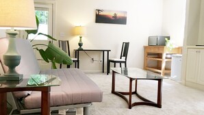 Un salon avec un canapé, une table basse en verre, une lampe, un téléviseur et un tableau au mur.