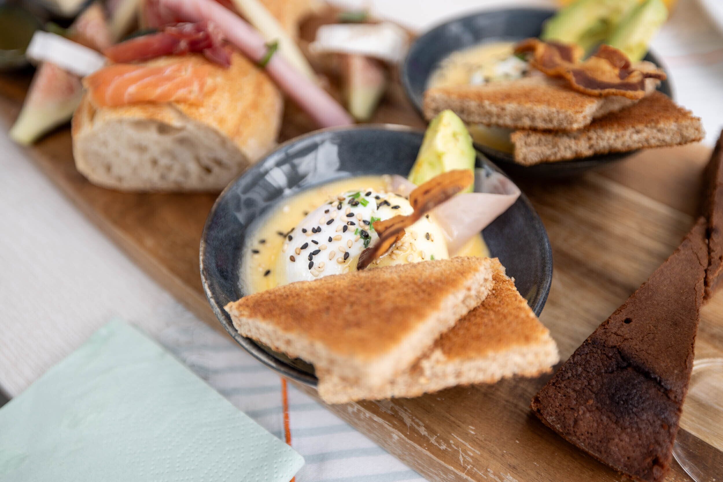 A variety of food items including bread, avocado, and a dish with a creamy sauce.