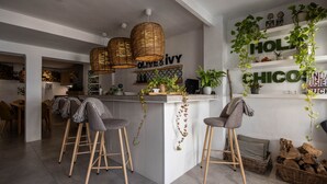 Eine moderne Küche mit einer zentralen Kochinsel, Barhocker, hängenden Pflanzen und einem 'HOLY CHICCO' Schild.