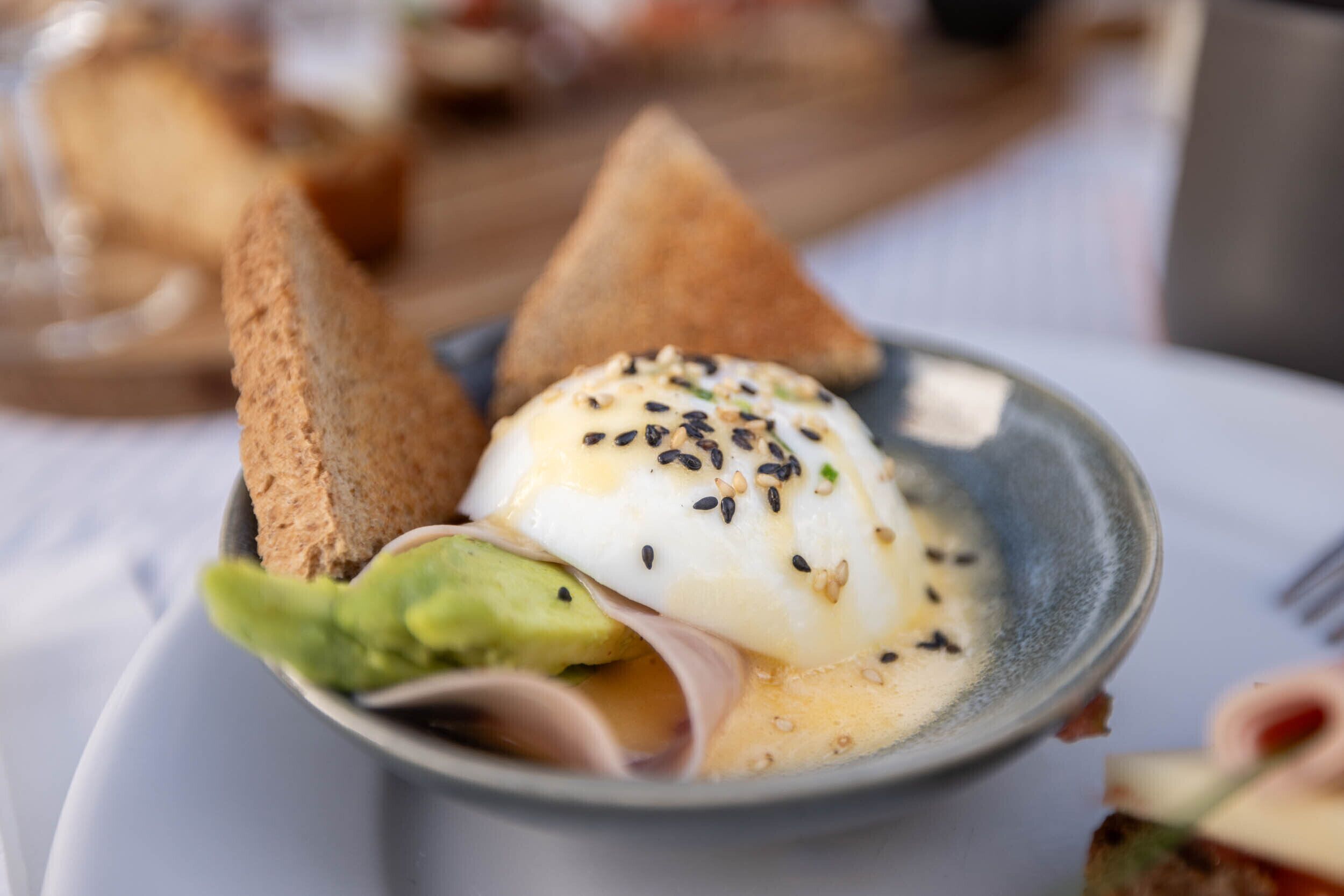 A bowl of food with a poached egg, avocado, and toast.