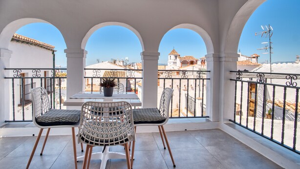Ein Balkon mit Tisch, zwei Stühlen und einem Blumentopf.