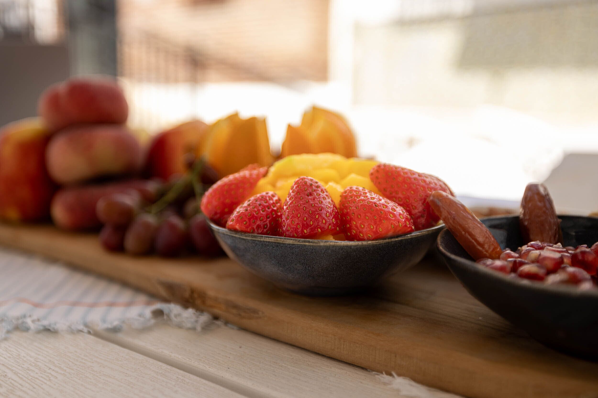 A wooden table with various fruits including strawberries, peaches, and grapes.