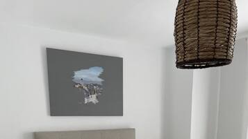 A modern bedroom with a bed, nightstands, a chair, and a hanging light fixture.