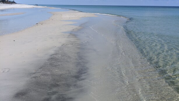 Una playa con agua cristalina y una orilla de arena.