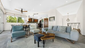 Uma sala de estar ampla com sofá, cadeiras, mesa de centro e área de jantar com mesa e cadeiras.