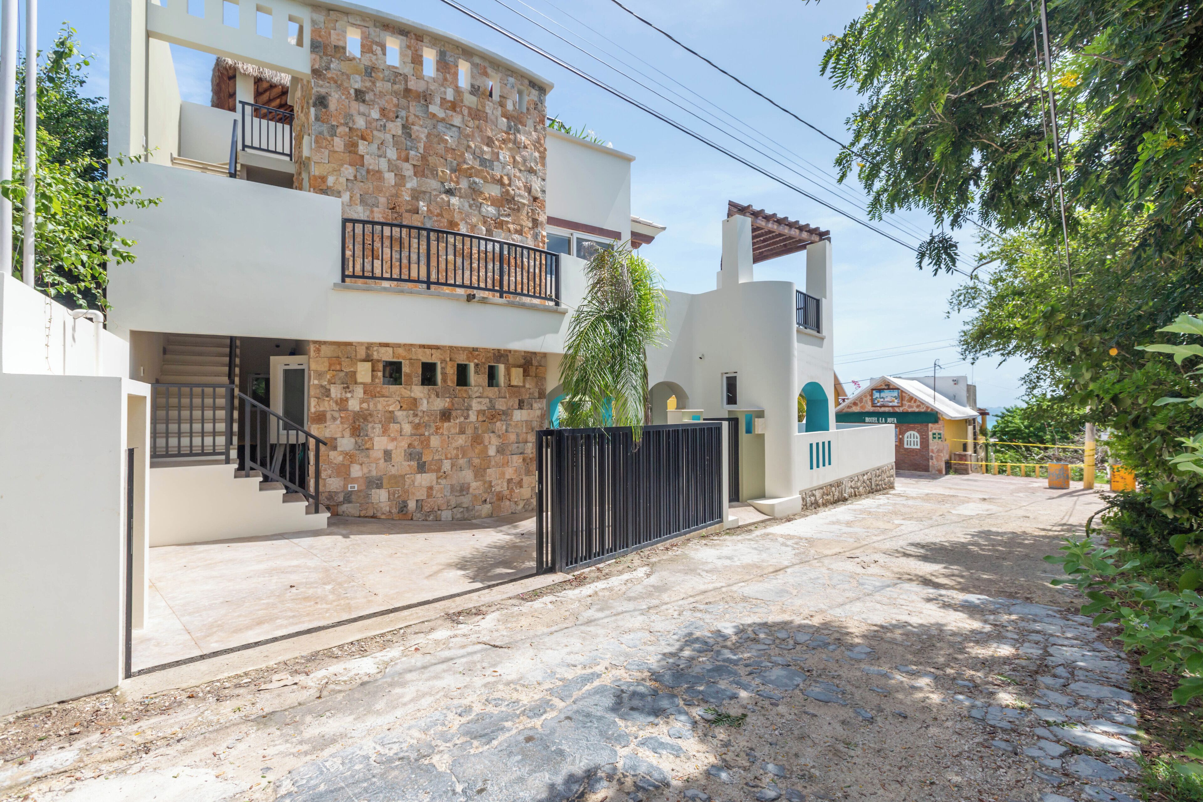 Una casa de dos pisos con fachada de piedra, un balcón y una entrada protegida por una reja.