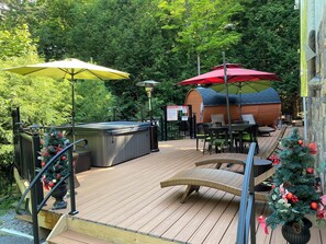 A wooden deck with outdoor seating, a hot tub, and a covered barbecue area. - Hottub, Sauna, Deck, Backyard, Hi-Speed Internet (Tannersville)