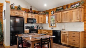 A kitchen with wooden cabinets, a black refrigerator, a microwave, and a dishwasher. - 2 BD Cabin near Branson Theatre District - Gas Fireplace & Whirlpool Tub,Ticket Discounts! (Branson)
