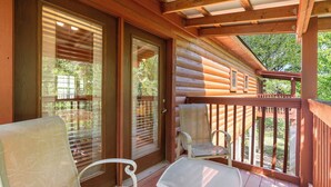 A wooden deck with a glass door leading to a covered porch area. - Romantic Walk-in Cabin for Two in the Heart of Branson - Jacuzzi Tub (Branson)