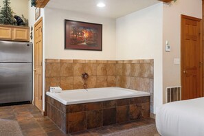 Une salle de bain avec une baignoire, un réfrigérateur et un meuble en bois.