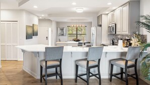 Een moderne keuken met een centraal eiland, barstoelen en inbouwapparatuur.