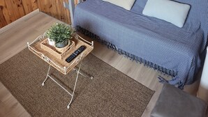 A cozy room with a wooden ceiling, a striped sofa with cushions, a small table with a plant and a remote control, and a brown rug. - Air-conditioned, fully renovated duplex with private terrace (Lunel)