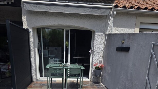 A patio with a table and chairs, a small garden area with gravel, and a stone staircase. - Air-conditioned, fully renovated duplex with private terrace (Lunel)