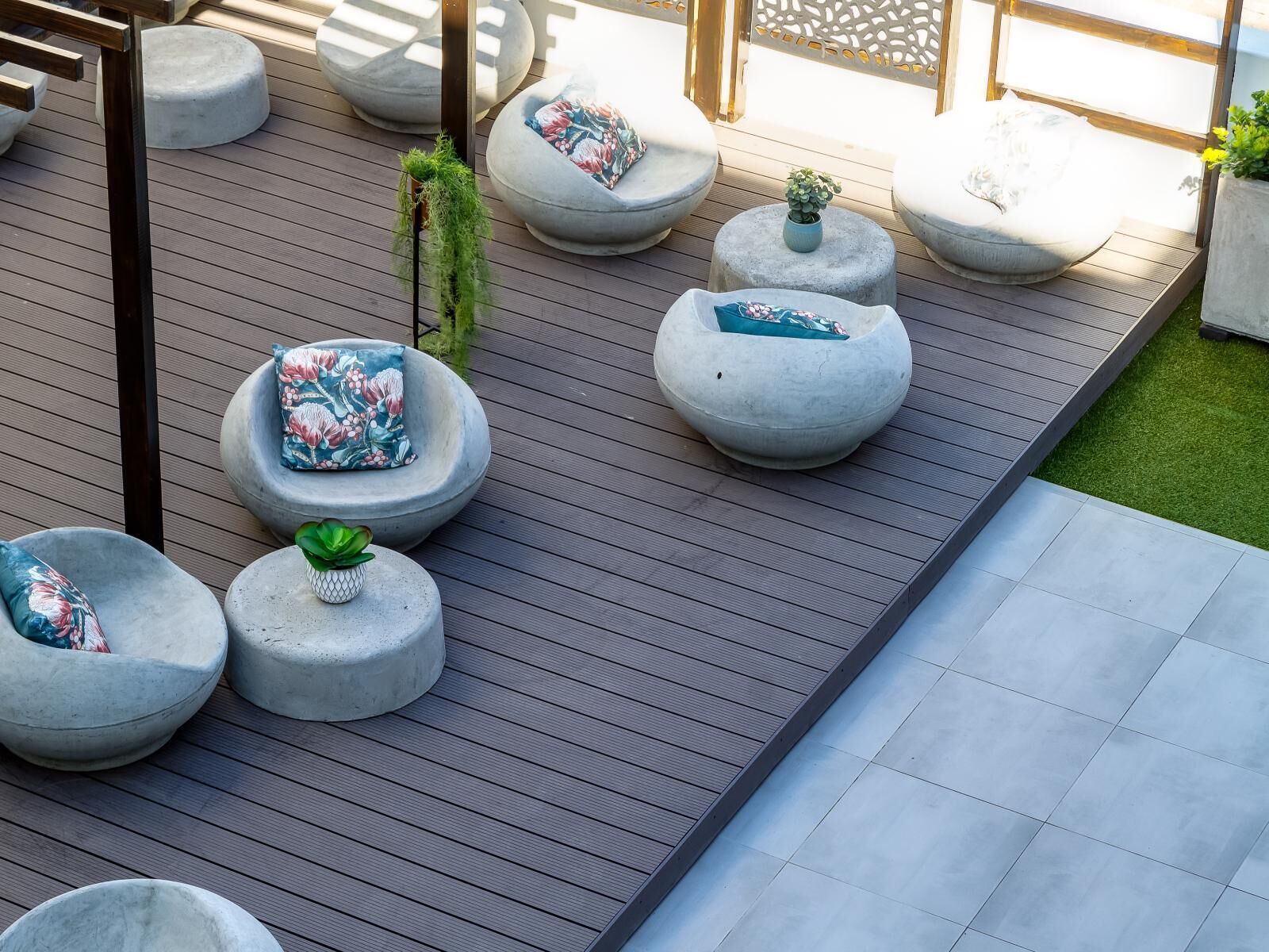 Eine Terrasse mit mehreren runden Sitzbereichen aus Stein, jeweils mit Kissen und einer kleinen Pflanze.