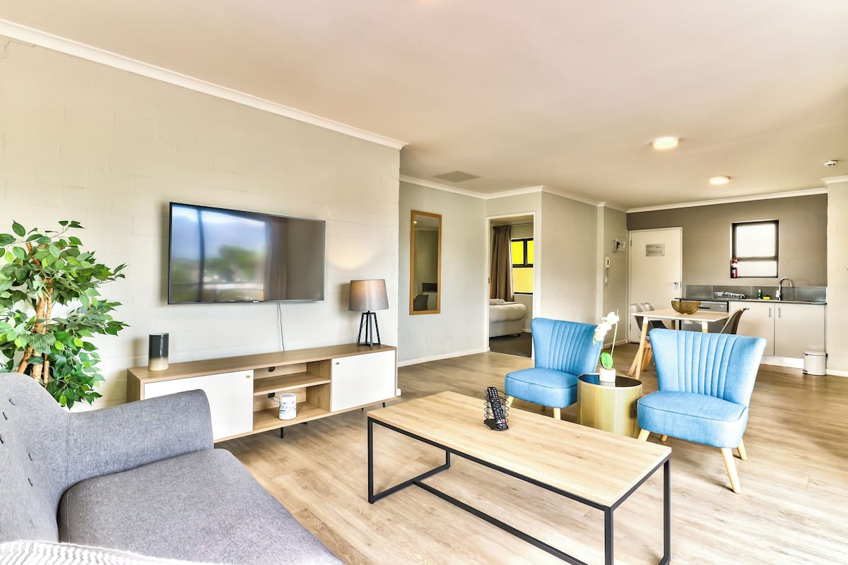 A modern living room with a sofa, a coffee table, a TV, and a plant.