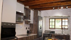 Een moderne keuken met houten kastjes, een ingebouwde oven en een eethoek met een tafel gedekt voor twee personen.