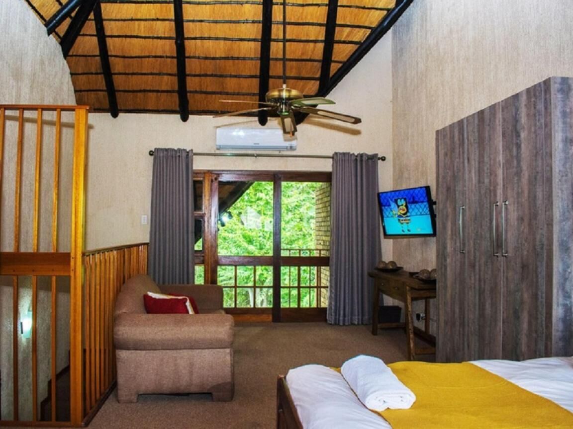 A room with a bed, a chair, a desk, a television, and a window with curtains.