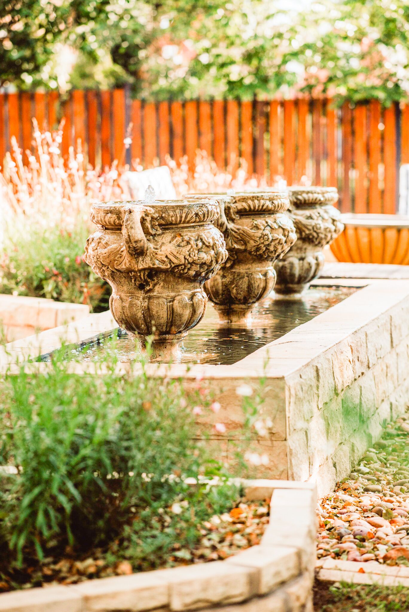 A garden with ornate stone planters and a wooden fence in the background.