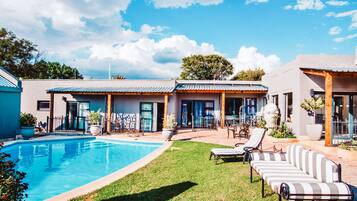 Una piscina al aire libre, sillones reclinables de piscina