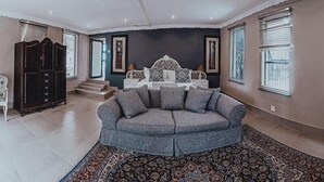 Een woonkamer met een grijze hoekbank, een donker houten kast en een kamerbreed tapijt met een patroon.