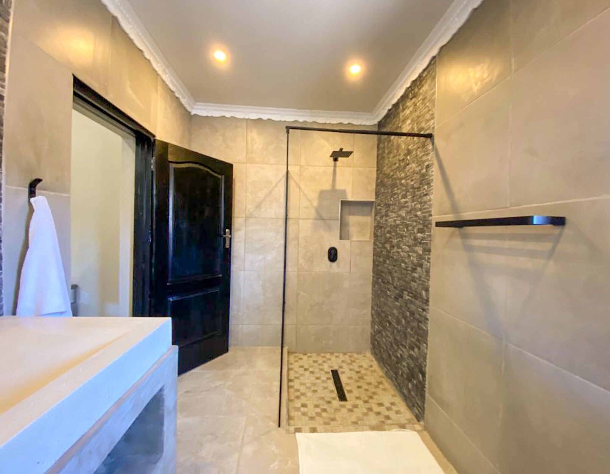 Un baño moderno con ducha, puerta de cristal y lavamanos blanco.