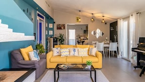 A modern living room with a sofa, coffee table, and dining area. - Sunset Bay Tecno Home Sardinia (Valledoria)