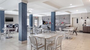 A modern hotel lobby with white furniture, a kitchen area, and a flat-screen TV mounted on the wall. - Best Western Plus Stephenville Inn (Stephenville)