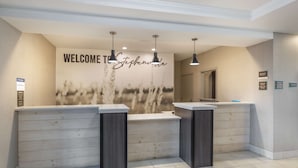A reception area with a 'Welcome to Stephen' sign, a counter, and a mirror. - Best Western Plus Stephenville Inn (Stephenville)