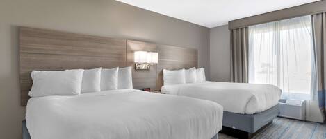 Habitación de hotel con dos camas, un ventanal con cortinas, una lámpara de pared y suelo alfombrado.