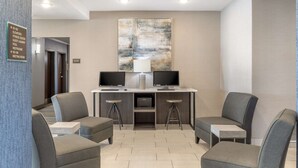 A lobby area with a reception desk, two monitors, and four grey armchairs. - Best Western Plus Stephenville Inn (Stephenville)