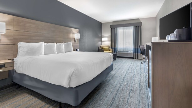 A modern hotel room with a large bed, bedside tables, a desk, and a flat-screen TV. - Best Western Plus Stephenville Inn (Stephenville)