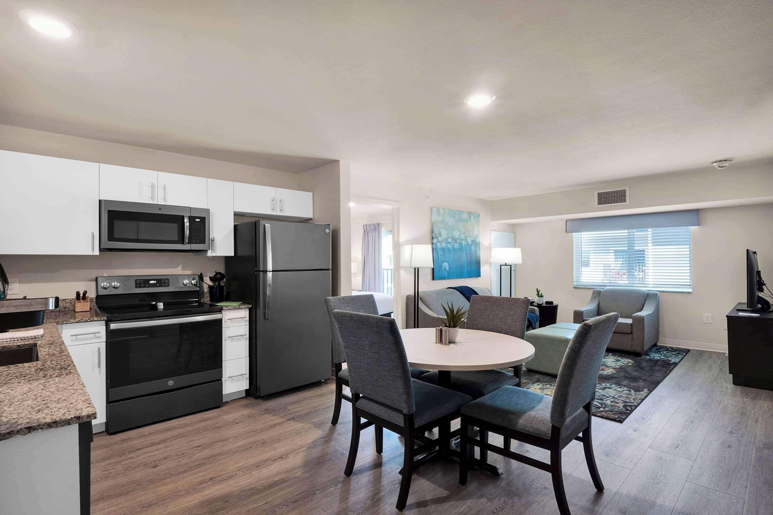 Cocina moderna con microondas, estufa y refrigerador. Cuenta con un comedor con mesa y sillas.