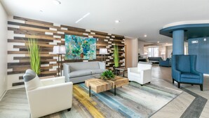 Un salon moderne avec un canapé, des fauteuils, une table basse et un tapis coloré.