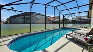 Une piscine dotée d’un bassin à eau cristalline, entourée d’une zone abritée dont la structure est faite d’un cadre métallique.