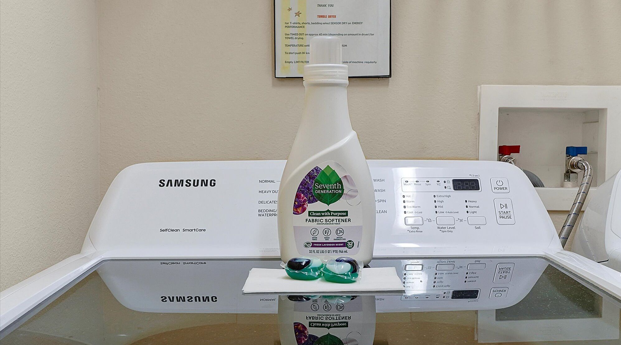 Eine Samsung Waschmaschine mit Selbstreinigungsfunktion, darüber ein Flakon von Seventh Generation Weichspüler.