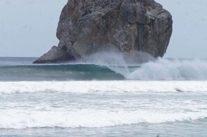 Una gran formación rocosa en el océano con olas rompiendo contra ella.