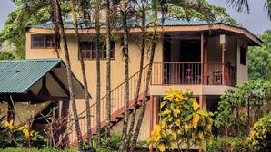 A two-story building with a balcony, surrounded by tropical vegetation. - Explore Paradise-Linda Vista cottage (Liberia)