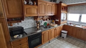 A kitchen with wooden cabinets, a stove, a sink, and a window with blinds.