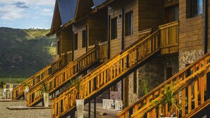 File d'habitacions de fusta amb escales exteriors, situades davant d'un paisatge amb pujols.