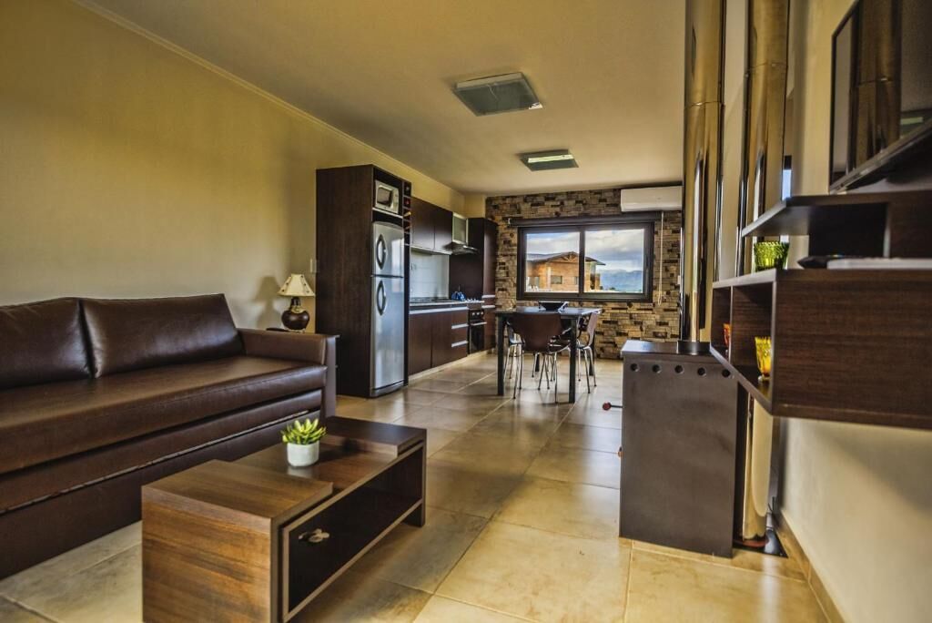 Een moderne woonkamer met een bank, salontafel en een keukenhoek met een eettafel en stoelen.