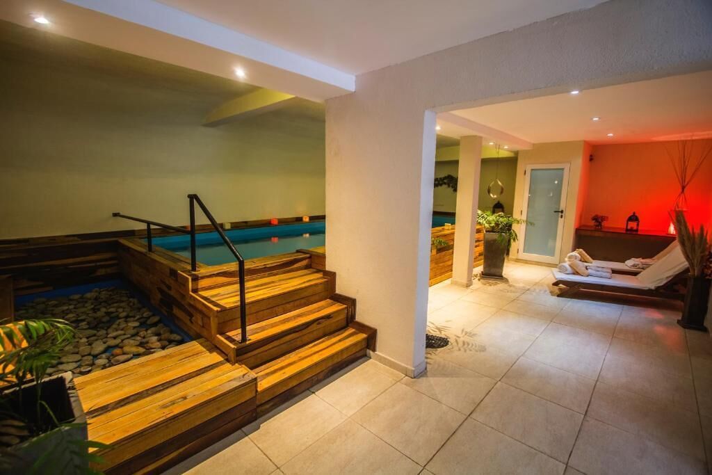 A spa area with a wooden staircase leading to a pool, a lounge with towels, and a potted plant.